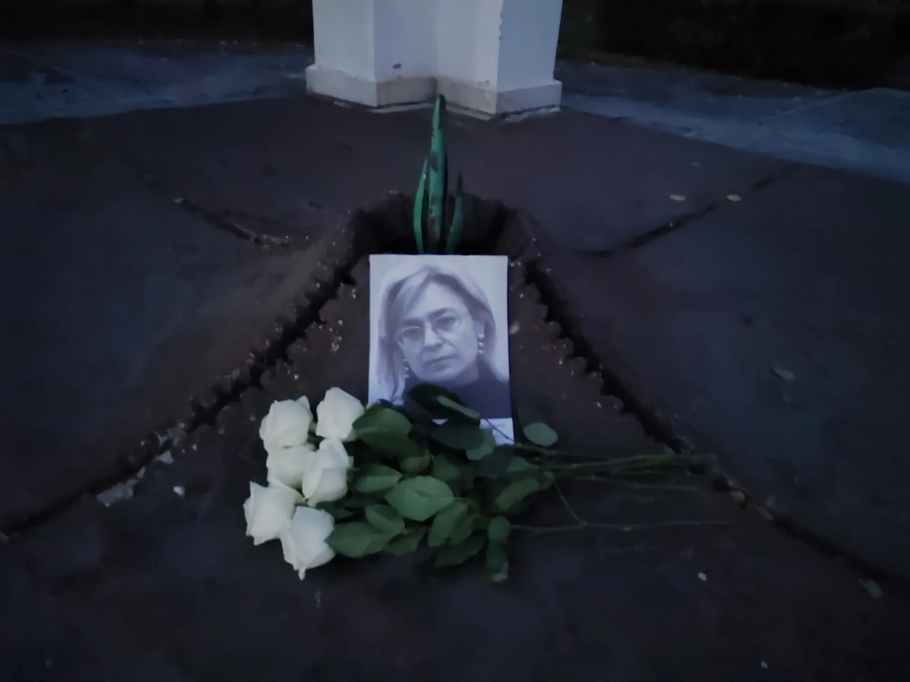 Портрет Анны Политковской и белые розы у памятника жертвам политических репрессий в Омске