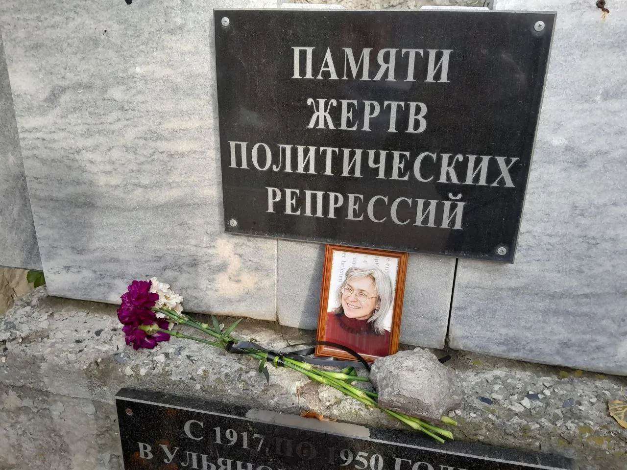 Портрет Анны Политковской и цветы у памятника жертвам политических репрессий